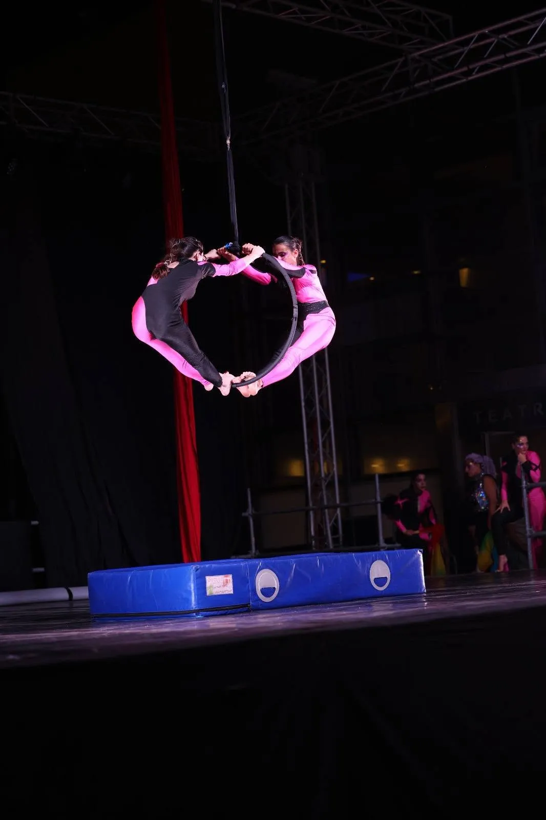 Due ballerine sospese al cerchio aereo, una di fronte all’altra, sul palco di uno spettacolo serale