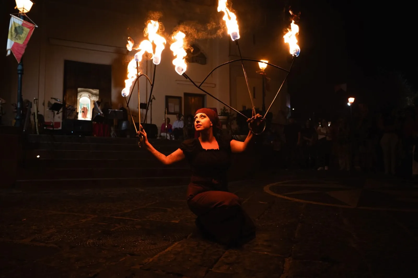 Judy Esposito durante una performance serale con i ventagli di fuoco, in piazza